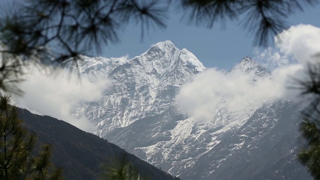 喜马拉雅山的山峰在云的观点下移动从树枝在前景视频素材