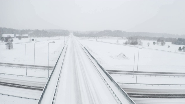 一架无人机在覆盖着道路和森林的厚厚的白雪上拍摄视频素材