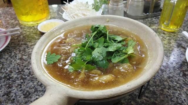 4k近距离拍摄在中国餐馆的砂锅中煮热腾腾的鱼胃、蟹肉和香菜汤。视频素材