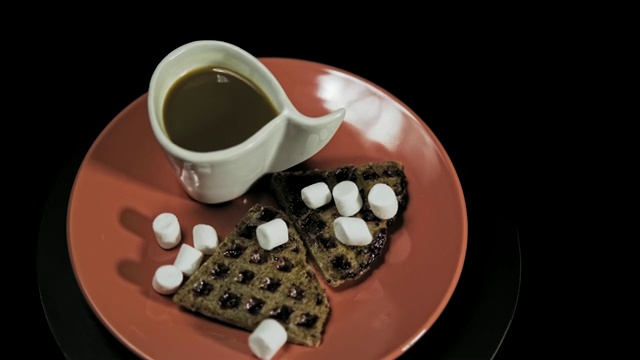 红色盘子上的黑心华夫饼，黑色背景的咖啡杯。视频素材