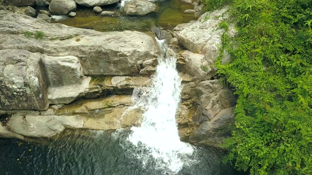 瀑布流动在野生雨林无人机的观点。高山瀑布和湖泊空中景观。流水流淌在热带丛林的山林湖泊中视频素材