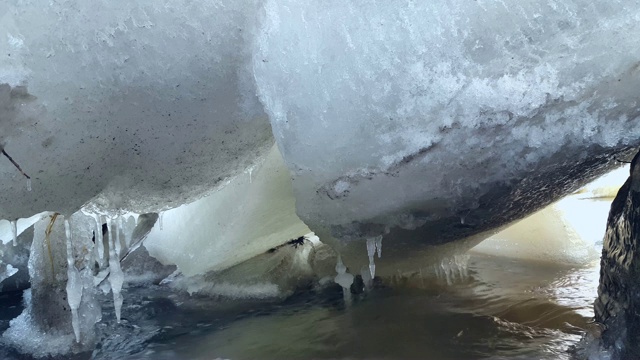 冻结河底的流水。冰下流动的河水。冬季冰冰川径流融雪。视频素材