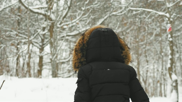 在大雪纷飞的冬日里，穿着舒适的皮大衣的漂亮年轻女人视频素材