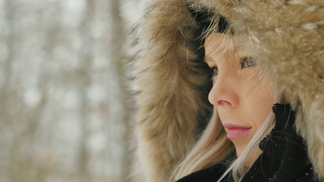 在大雪纷飞的冬日里，穿着舒适的皮大衣的漂亮年轻女人视频素材