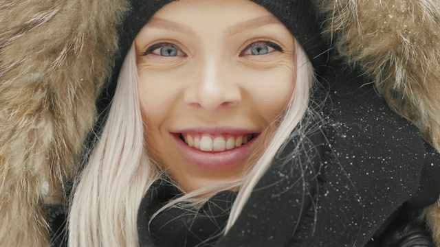 在大雪纷飞的冬日里，穿着舒适的皮大衣的漂亮年轻女人视频素材