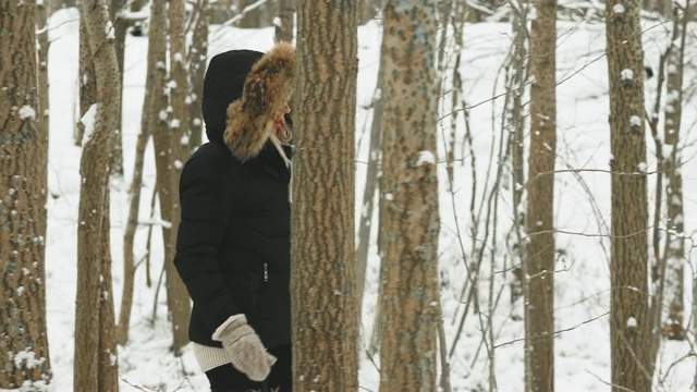 在大雪纷飞的冬日里，穿着舒适的皮大衣的漂亮年轻女人视频素材