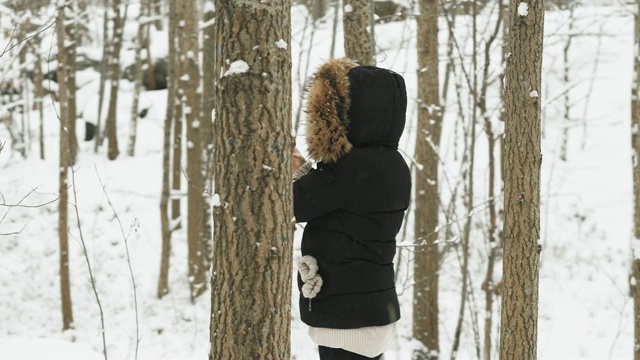 在大雪纷飞的冬日里，穿着舒适的皮大衣的漂亮年轻女人视频素材