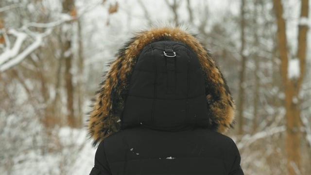 在大雪纷飞的冬日里，穿着舒适的皮大衣的漂亮年轻女人视频素材