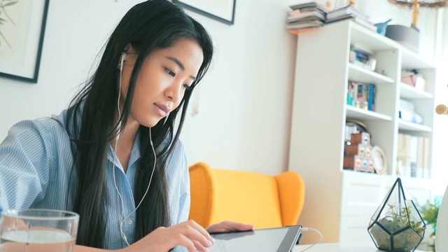 一个亚洲女人在听播客。视频素材