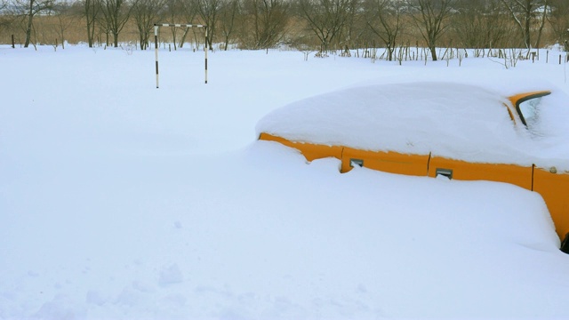 汽车被雪覆盖，在严冬的暴风雪中。车在院子里下着雪。视频素材