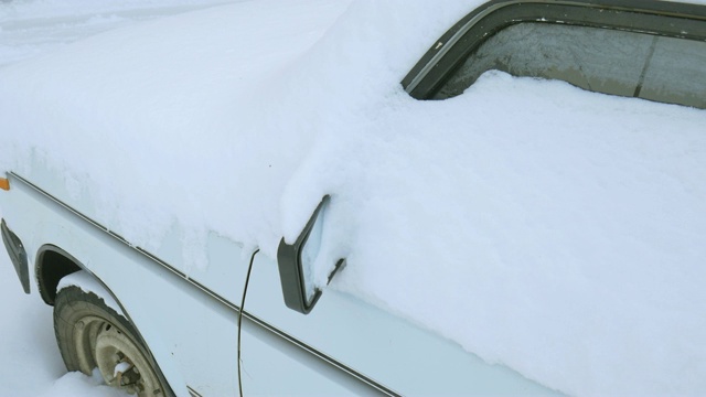 汽车被雪覆盖，在严冬的暴风雪中。车在院子里下着雪。视频素材