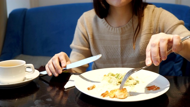 一个面无表情的女人在咖啡馆用刀叉吃蔬菜沙拉视频素材