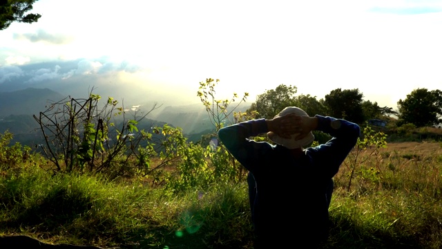 一个隐士在山的边缘迎接日出。在阳光下冥想。视频素材