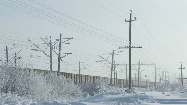 冬季火车与货车，电线传输覆盖着霜，植物覆盖着雪视频素材