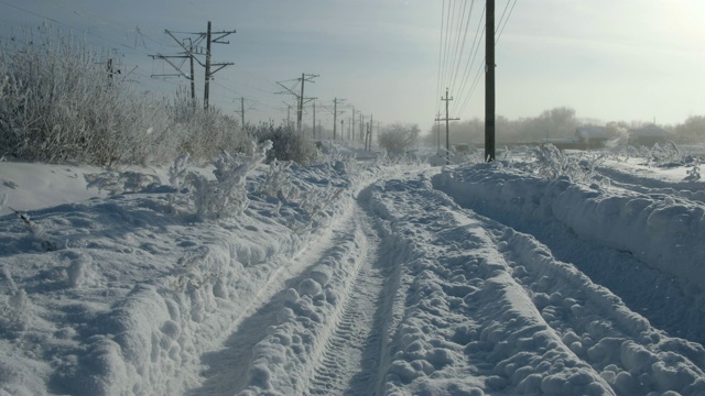 冬天的俄罗斯村庄里冰雪覆盖的道路，铁路附近，树木和植物被美丽的冰雪覆盖视频素材