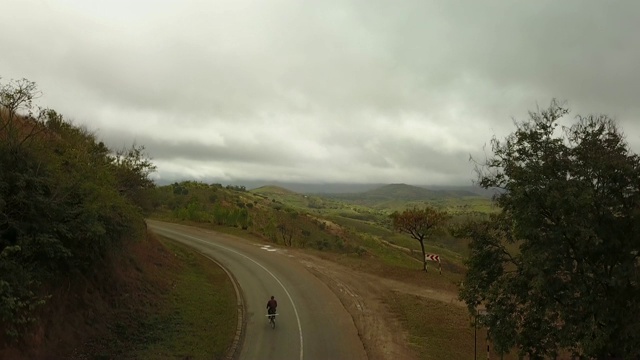 空中升起的农村非洲公路通过山区与骑自行车的人视频素材