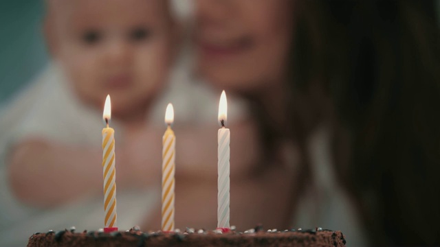 妈妈在宝宝生日蛋糕上吹三支蜡烛。宝宝生日派对概念视频素材