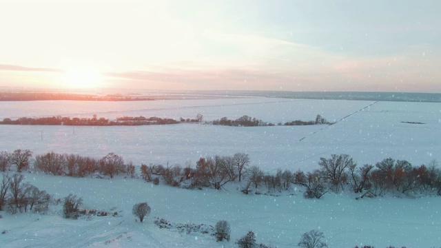 4k鸟瞰图，飘落的雪在一个冬天晴朗的一天日落视频素材