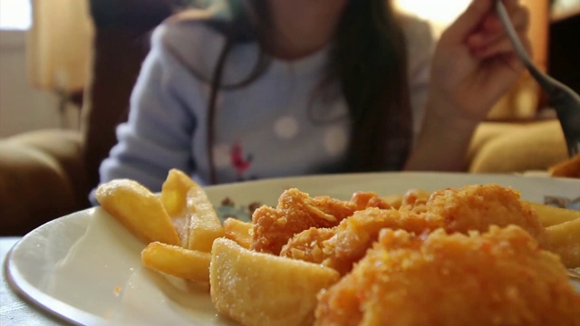 女孩吃着快餐——炸薯条和鸡肉视频素材