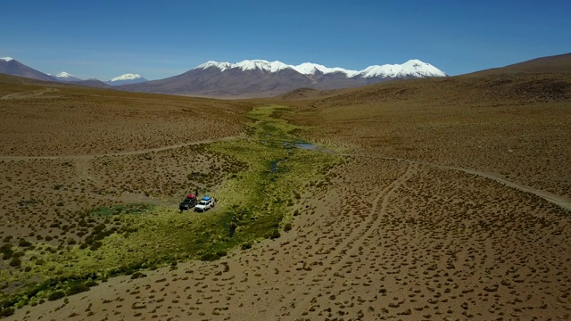 Altiplano山谷内的安第斯山脉在通往乌尤尼盐滩的道路上，一个惊人的风景从无人机上俯瞰4x4汽车和人们在绿色山谷玻利维亚旅行视频素材