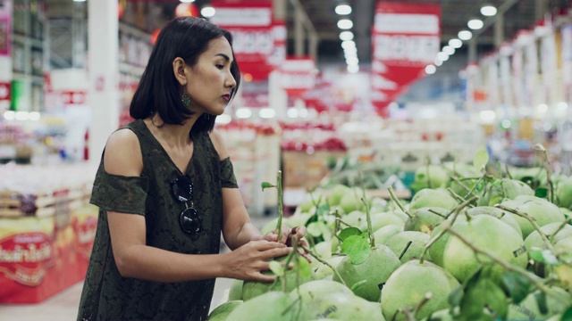 年轻美丽的亚洲女人在超市买柚子。视频素材