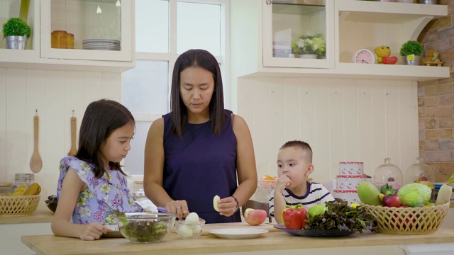 母亲和孩子在厨房里一起准备蔬菜和沙拉，快乐的家庭理念视频素材