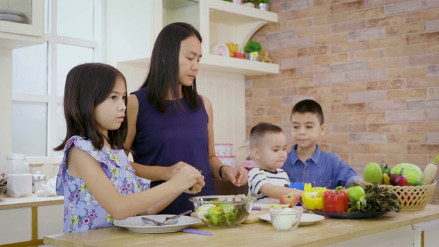 母亲和孩子在厨房里一起准备蔬菜和沙拉，快乐的家庭理念视频素材