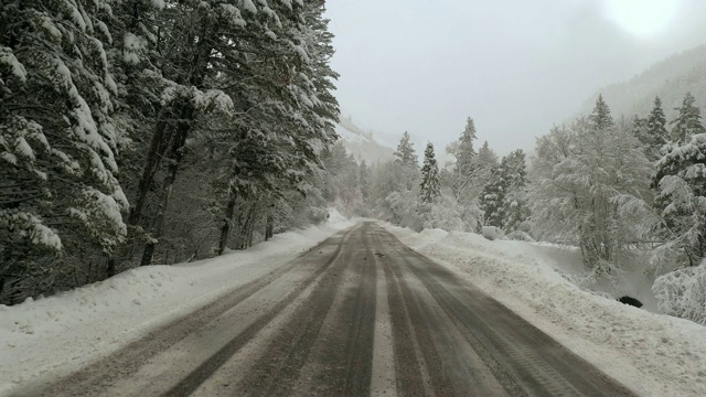 在暴风雪中穿越峡谷，沿着结冰的道路飞行视频素材