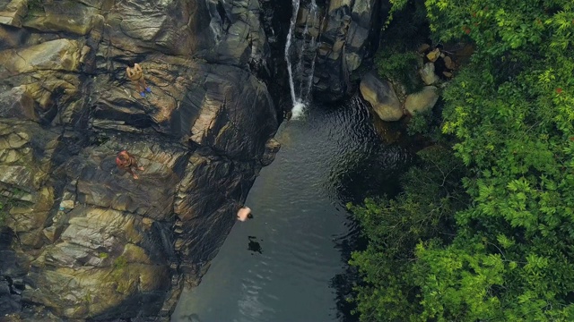 游客在热带雨林空中景观的高山瀑布中跳水、游泳。人们在丛林里跳着从山上瀑布流下的河水视频素材