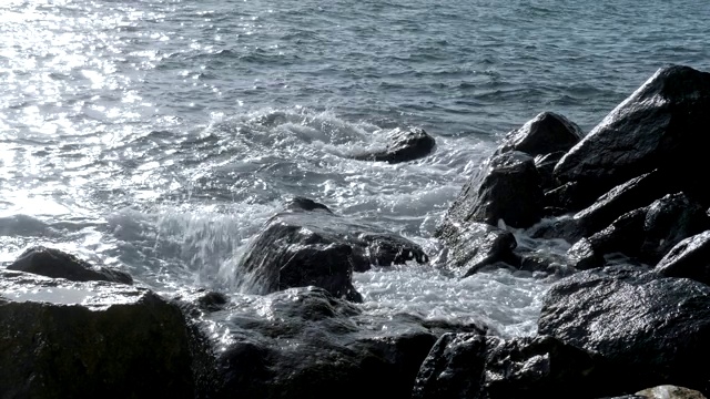 海景与水溅在岩石上，阳光闪烁，近距离的观点。视频素材