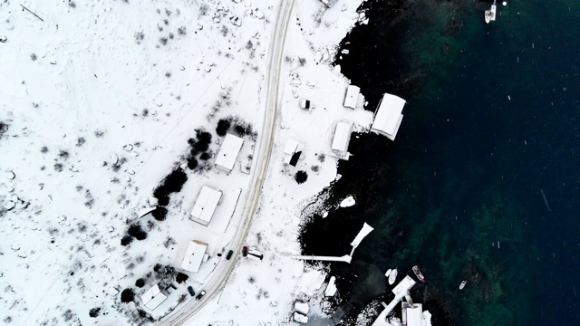 在冬季暴风雪中，汽车在靠近北极海岸线的道路上行驶的鸟瞰图视频素材