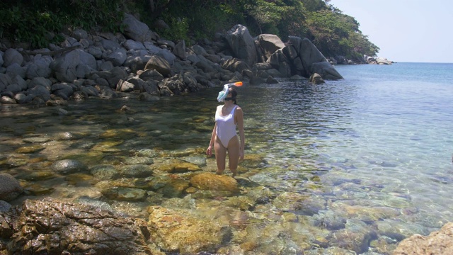 年轻女子浮潜在蓝色的热带水穿着白色泳衣视频素材