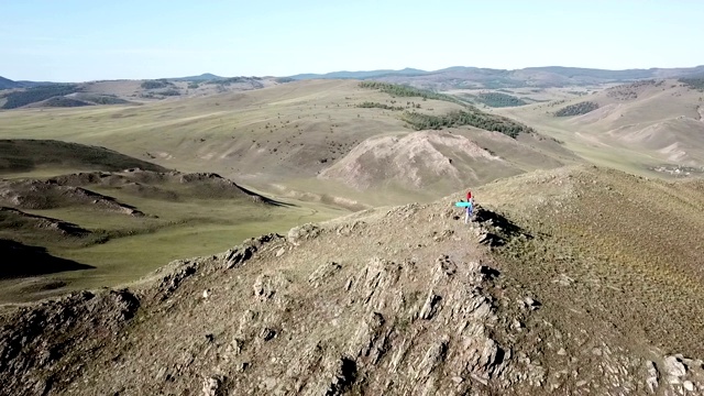 空中-一个人站在山顶上的剪影。女人爬完山后胜利地举起双臂视频素材