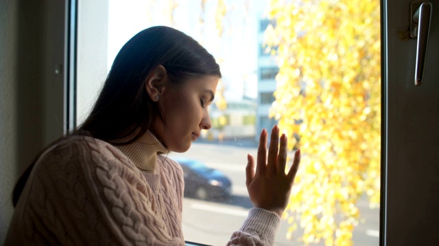 年轻女子透过窗户哭泣，生活和健康问题，抑郁视频素材