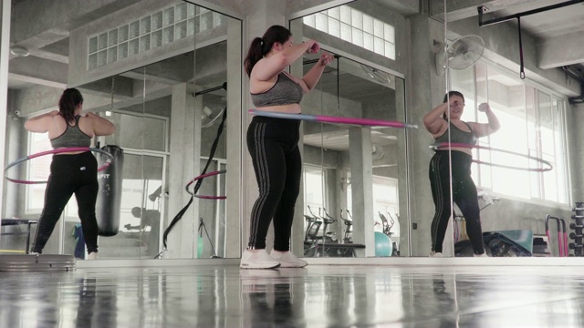 胖女人在健身房里玩呼啦圈。视频素材
