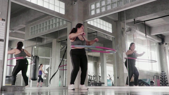(慢镜头)超重女子在健身房里玩呼啦圈。视频素材
