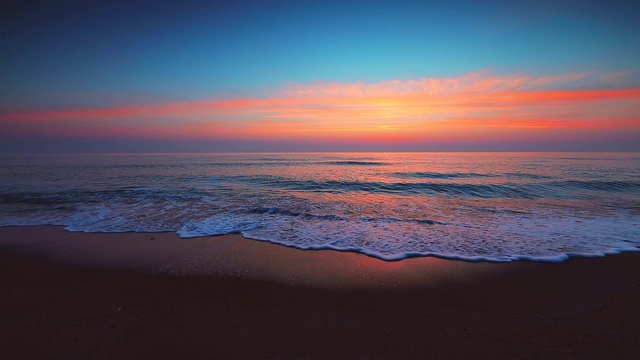 海面和海滩上的日出。海浪冲刷着沙滩视频素材