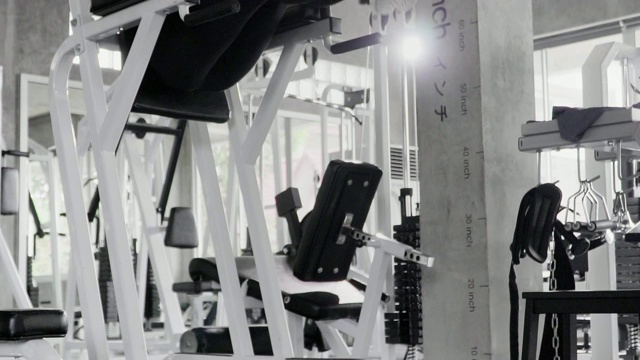(慢镜头)在健身房里用器械锻炼女性体重。视频素材