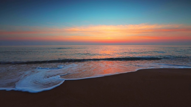 海面和海滩上的日出。海浪冲刷着沙滩视频素材