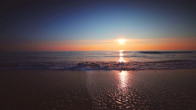 海面和海滩上的日出。海浪冲刷着沙滩视频素材