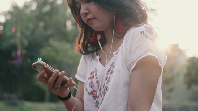 年轻女子坐在瀑布边听音乐。视频素材