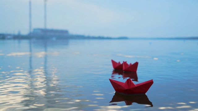 模糊的背景上，幼稚的纸船漂浮在水面上。视频素材