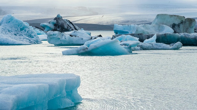 美丽的蓝色冰在冰岛的Jokulsarlon冰湖，背景是欧洲最大的冰川Vatnajokull视频素材