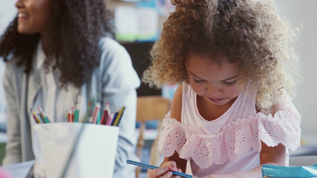 混血女学生在一所幼儿学校的教室里选择一支铅笔，有选择的焦点视频素材