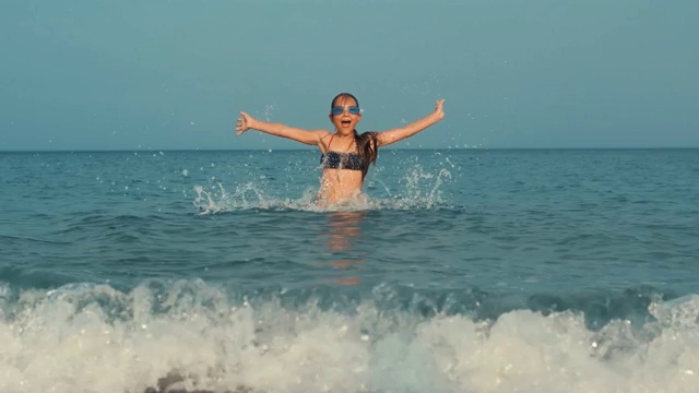 年轻女孩在海水中跳跃。在海里游泳的少年视频素材