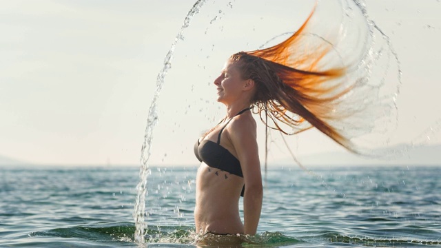 站在海里的女人，把湿漉漉的头发向后甩视频素材