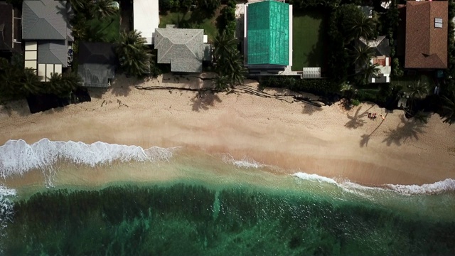 鸟瞰图:海滩房产与海浪打破在沙滩上视频素材