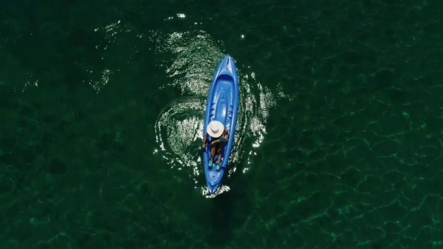 一个孤独的女人在湖上或海上划皮艇。一个快乐的成熟女人在一个夏天的湖中或海里划独木舟。视频素材