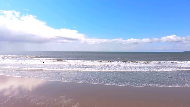 男性冲浪者站在海滩冲浪板在一个晴朗的日子4k视频素材