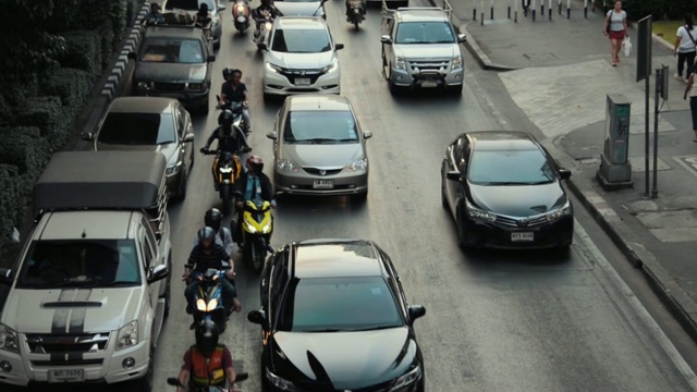 从上面俯瞰曼谷的交通，日落，汽车和公共汽车沿着道路行驶，自行车在其间穿梭。视频素材